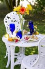 Vista diurna del tavolo esterno con colazione a waffle belga, fiori in vaso — Foto stock
