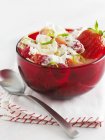 Nahaufnahme eines Desserts mit Erdbeeren und Limettenschale in roter Schüssel — Stockfoto
