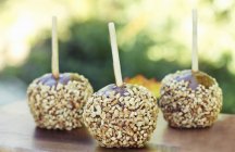 Closeup view of three caramel apples coated with chopped nuts — Stock Photo