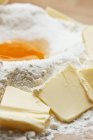Vista close-up de pedaços de manteiga com amontoamento de farinha e gema de ovo — Fotografia de Stock