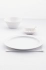 Primo piano vista di un luogo bianco impostazione con ciotole, un piatto, un cucchiaio e un tovagliolo piegato — Foto stock