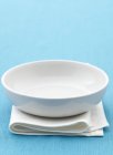 Вид крупным планом одной белой тарелки на сложенном полотенце и голубой поверхности — стоковое фото