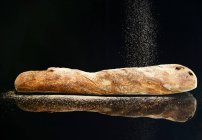 Baguette being sprinkled with flour — Stock Photo