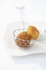 Closeup view of fried dumplings in wire skimmer on white dish — Stock Photo