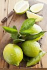 Frische grüne Zitronen mit Blättern — Stockfoto