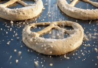 Unbaked pretzels being sprinkled with salt — Stock Photo