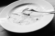 Closeup view of dirty white plate with vegetable and sauce leftovers and fork — Stock Photo