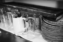 Вид крупным планом на очки со столовыми приборами и стопкой тарелок — стоковое фото