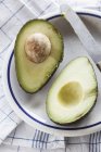 Avocado halbiert auf weißem Teller — Stockfoto