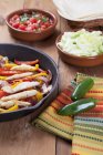 Chicken Fajita Skillet with Toppings and Jalapeno on wooden surface — Stock Photo