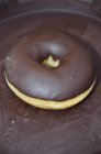 Крупный план одного шоколадного пончика с глазурью — стоковое фото
