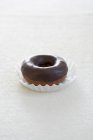 Nahaufnahme von Schokolade glasierten Donut auf Pappbecher und weißer Oberfläche — Stockfoto