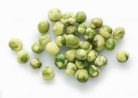Wasabi peas scattered on white surface — Stock Photo