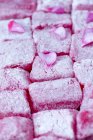 Nahaufnahme der türkischen Freude an Zuckerguss und rosa Blütenblättern — Stockfoto
