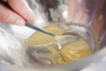 Vue rapprochée de la crème à collecter à la main dans un bol à mélanger avec une cuillère — Photo de stock