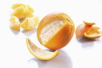 Naranja fresca parcialmente pelada con segmentos - foto de stock