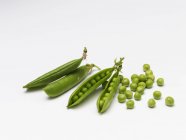 Ripe pea pods on a white surface — Stock Photo
