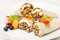 Closeup view of Burritos and fruit on a white plate — Stock Photo
