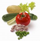 Bodegón vegetal con tomate, pepino, guisantes, frijoles y patata sobre fondo blanco - foto de stock