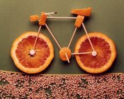 Vista de cerca de la bicicleta hecha de rodajas de naranja y palillos de dientes - foto de stock