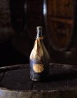 Uma garrafa de vinho antigo com etiquetas em um velho barril de madeira — Fotografia de Stock