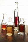 Vista close-up de quatro garrafas de vidro sortidas de vinagres — Fotografia de Stock