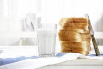 Pila di pane tostato e un bicchiere di latte — Foto stock