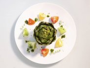 An artichoke with tomatoes and pesto  on white plate — Stock Photo