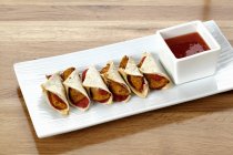 Elevated view of mini wraps with barbecue sauce — Stock Photo