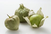 Three tomatillos laying over white surface — Stock Photo