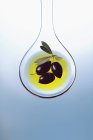 Оливковое масло и оливки на ложке салата — стоковое фото