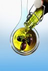 Оливковое масло льется на оливки — стоковое фото