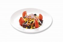 Salade de maïs aux tomates et oignons sur assiette blanche — Photo de stock