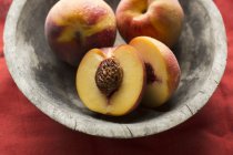 Свежие персики в деревянной чаше — стоковое фото