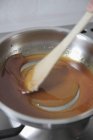 Vista de primer plano de la mezcla de azúcar caramelizante en la sartén con espátula - foto de stock