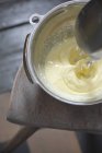 Vue surélevée du mélange des œufs et de la crème dans un bol en métal sur chaise — Photo de stock