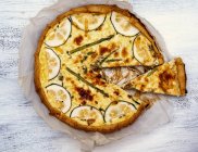 An asparagus and courgette Quiche, sliced on baking paper — Stock Photo