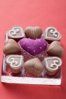 Coração tecido cercado por chocolates — Fotografia de Stock