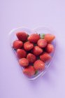 Fresas en un recipiente en forma de corazón - foto de stock