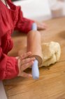 Closeup view of child with rolling pin and ball of dough — Stock Photo