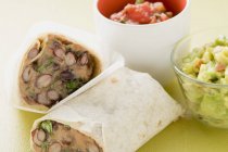 Bohnenburritos, Guacamole und Salsa in kleinen Schalen über grüner Oberfläche — Stockfoto