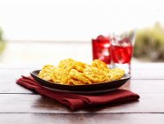 Closeup view of crispy pepper chips on plate and folded napkin — Stock Photo
