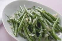 Grüne Bohnen mit Zwiebeln auf weißem Teller — Stockfoto