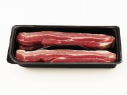 Bacon cru dans l'emballage — Photo de stock