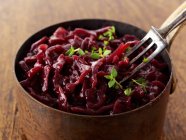 Closeup view of red cabbage in a pan with fork on wooden surface — Stock Photo