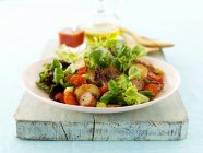 Closeup view of mixed leaf salad with fried potatoes and sausage — Stock Photo