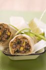 Bean burritos with lime in small dish over green surface — Stock Photo