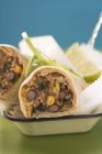 Bean burritos with lime in dish over table — Stock Photo