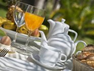 Сніданок на садовому столі з чайниками та келихами на відкритому повітрі — стокове фото