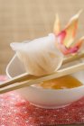 Dim sum on chopsticks over dip — Stock Photo